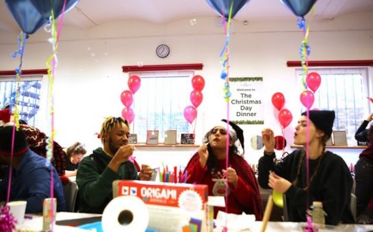 Three young care leavers blow bubbles sat around a table at a Richmond Christmas Day Dinner party