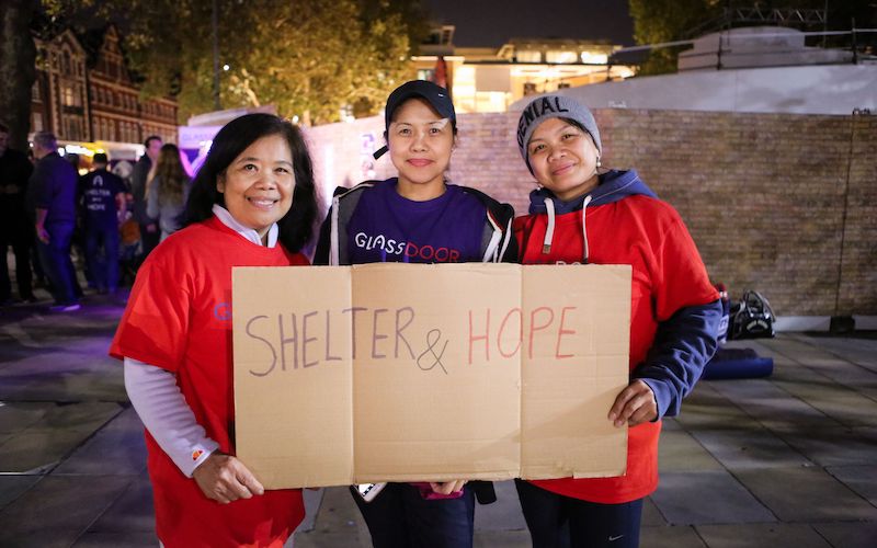 Three people hold sign saying Shelter & Hope
