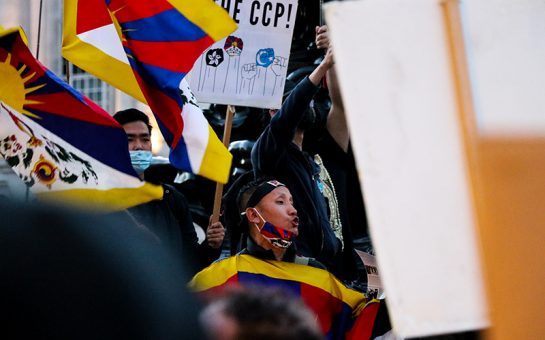 Protestor, dressed in a Tibetan flag, shouts to crowds