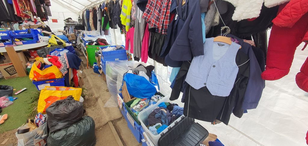 One wall of a large tent with hundreds of clothes on racking 