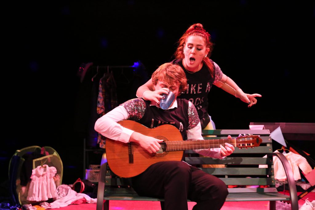 Georgie Halford as Doll distracts Roel Fox as Ted as he plays guitar in Epic Love and Pop Songs 