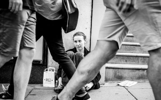 Homeless woman sitting on a pavement