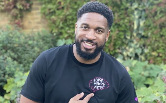 A man wearing a Young Goat black t-shirt, pointing to the Black Minds Matter sign on the t-shirt