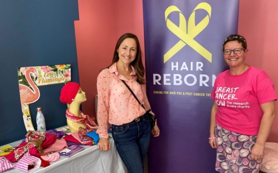 Anna Godsiff and Lina Milazzo smilimg in front a Hair Reborn stand with headwraps