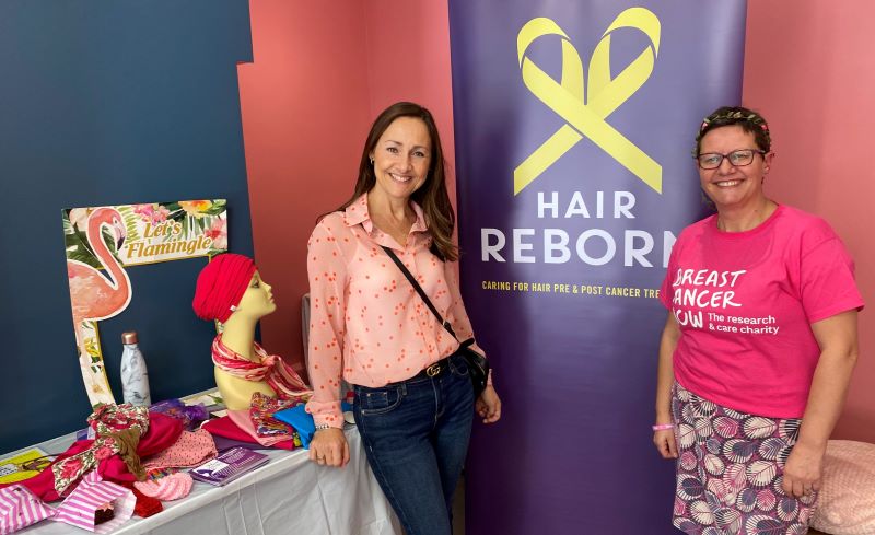 Anna Godsiff and Lina Milazzo smilimg in front a Hair Reborn stand with headwraps