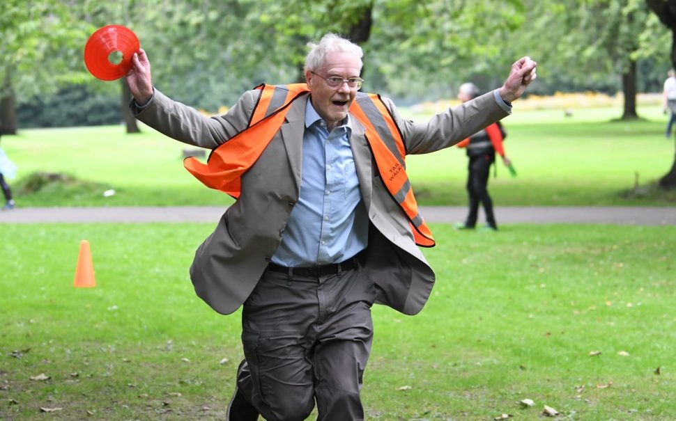 An elderly man in a high-vis vest finishes parkrun