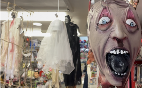 A terrifying mask hangs from the ceiling of a halloween party shop