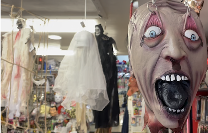 A terrifying mask hangs from the ceiling of a halloween party shop