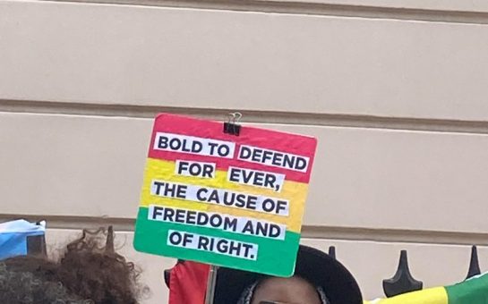 Protest sign with the Ghana flag colours about defending freedom
