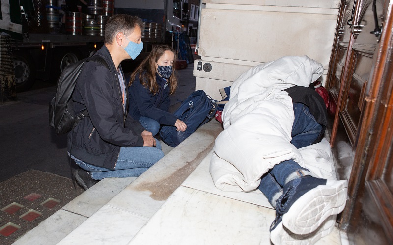 Members of the Westminster street outreach service talk with a rough sleeper in the doorway of a building.