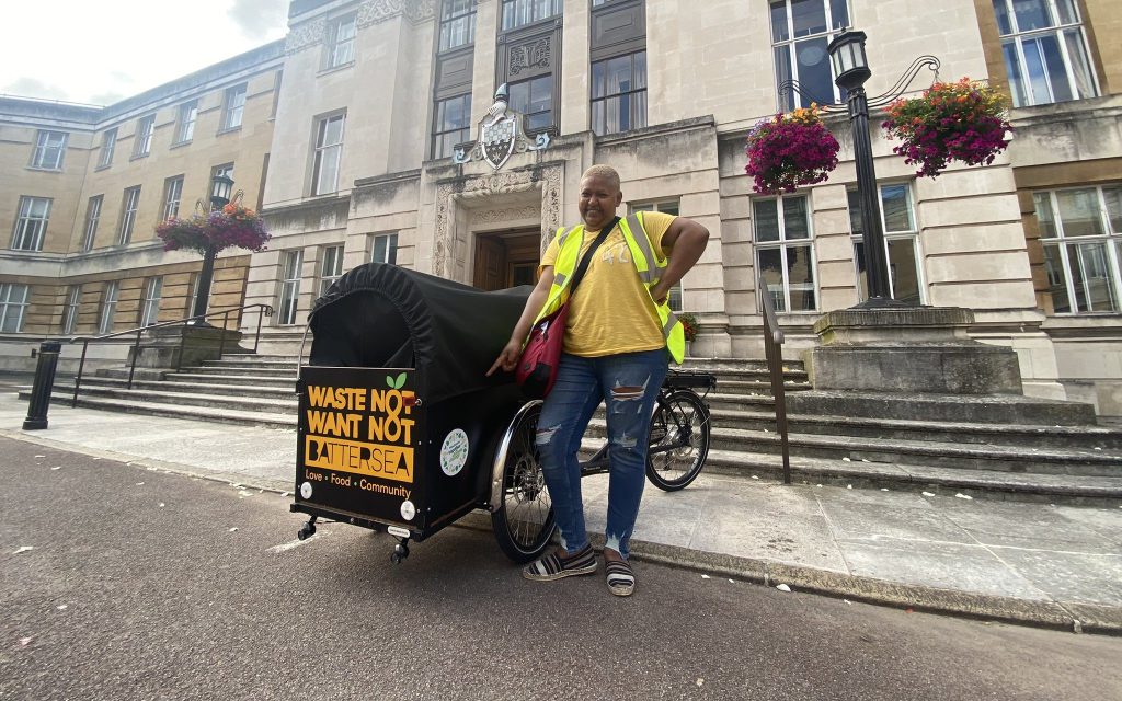 A member of Waste Not Want Not stands beside a cargo bike
