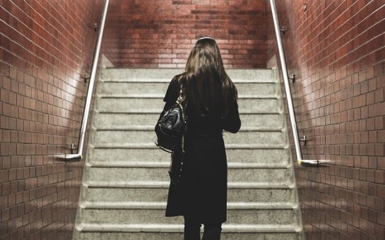Image of a woman with her back to the camera walking alone at night in a station