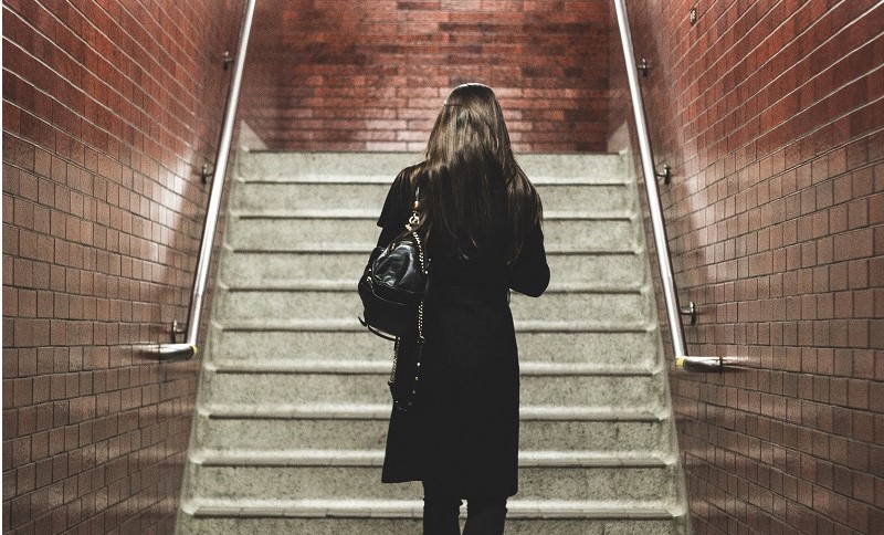 Image of a woman with her back to the camera walking alone at night in a station