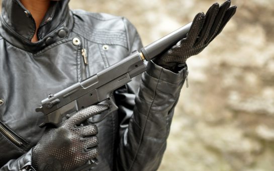 A person holding a pistol with a silencer on it