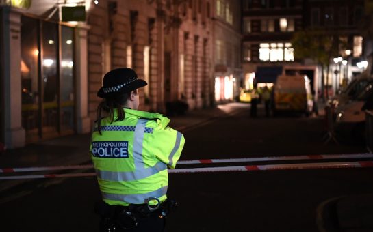 A police officer stands looks down the road
