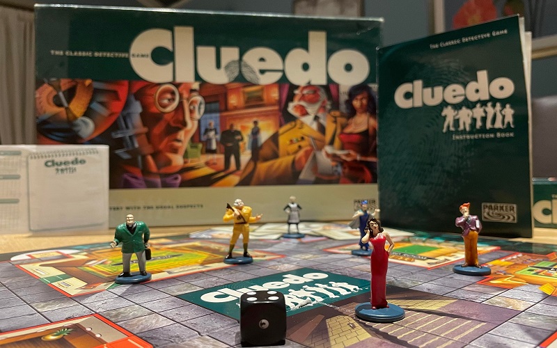 Miss Scarlett stands in front of the five over suspects on a Cluedo board