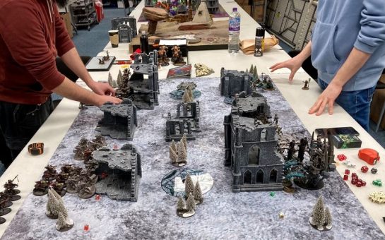 Two gamers in the process of setting up a Warhammer table
