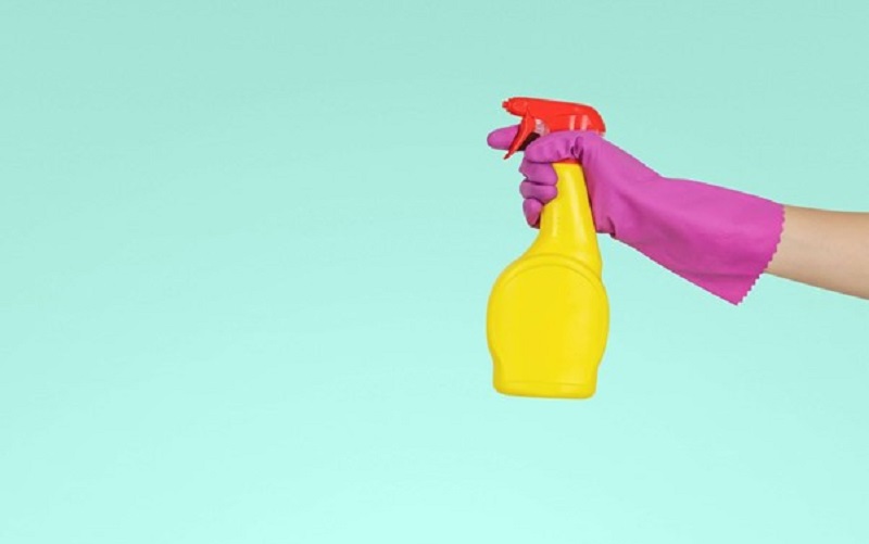 a yellow spray bottle against a teal background