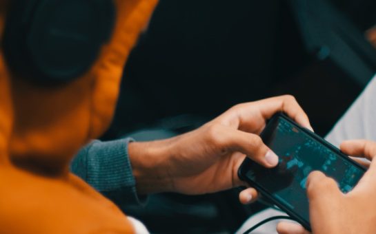 man with headphones playing mobile game
