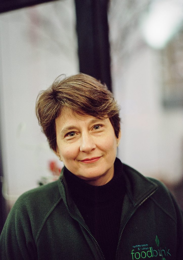 Photo of caucasian woman, profile of shoulders and face wearing a green fleece. The fleece has words reading "hammersmith and fulham foodbank"