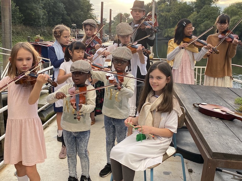 STUDENTS ON A BOAT PERFORMING FOR SETTLERS