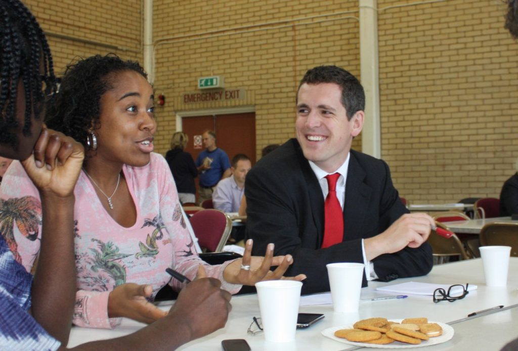 Labour Councillor Hogg who is campaigning for more council housing in Wandsworth, is seen talking to young people sat around a table 