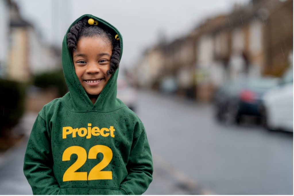 Exterior picture of Naomi wearing a Project 22 hoodie on a street.