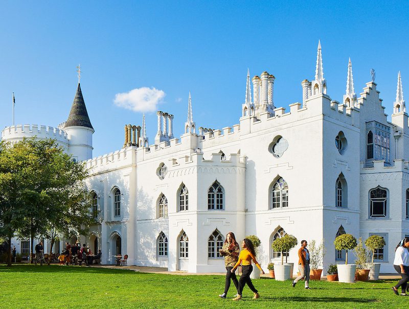 The campus of St Mary's University Twickenham, showing an old white building and students walking across the grass