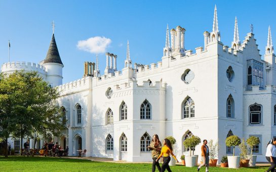 The campus of St Mary's University Twickenham, showing an old white building and students walking across the grass