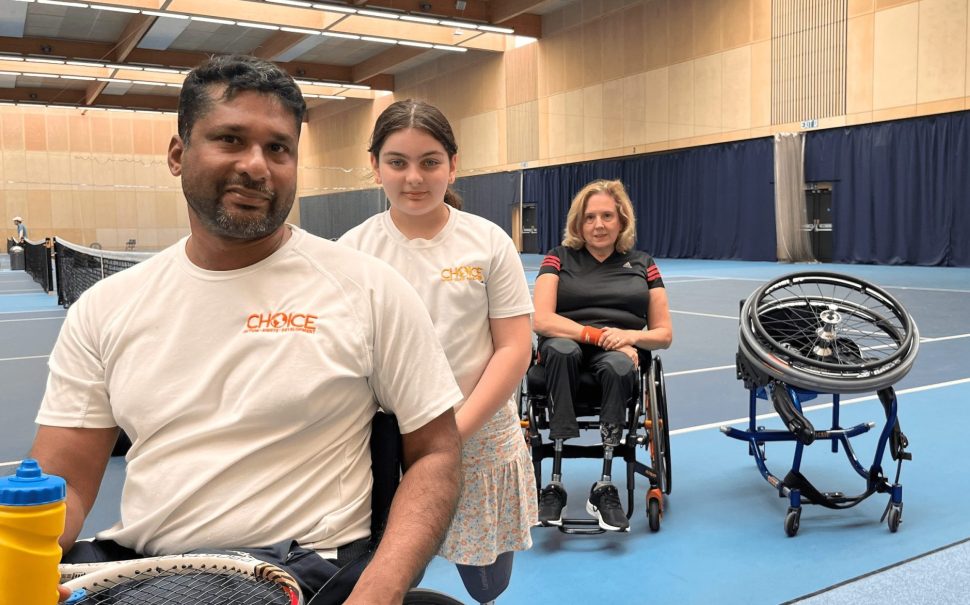 Wheelchair tennis team, 3 members of a team a man on the left, a young girl in the middle and a woman on the right all three siting on a wheelchair