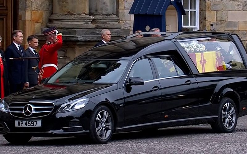 Queen Elizabeth's coffin wrapped in the Royal Standard of Scotland with a wreath of her favourite flowers from the Balmoral estate. Via iPlayer.