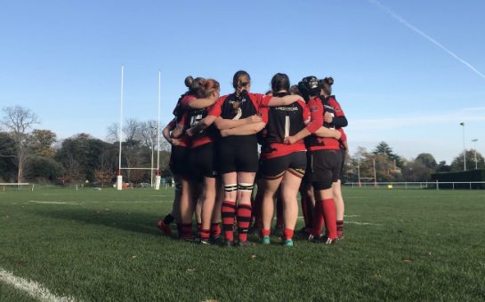 London Welsh Women group huddle before a league game with posts in the background