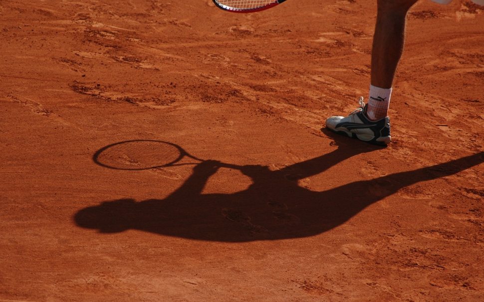 A silhouette on a clay court