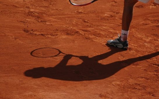 A silhouette on a clay court