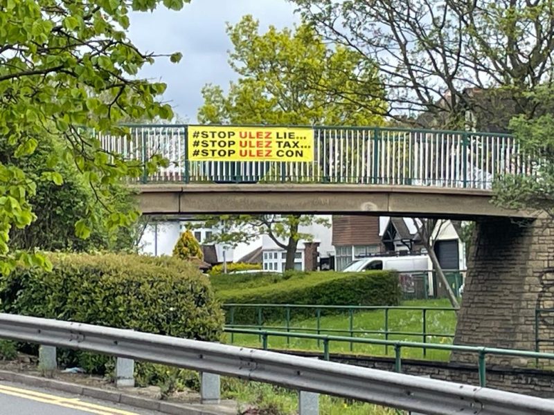 A ULEZ protest banner over a bridge in Sutton reading: #STOP ULEZ LIE... #STOP ULEZ TAX... # STOP ULEZ CON