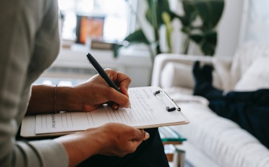 Psychologist writing on clipboard during session