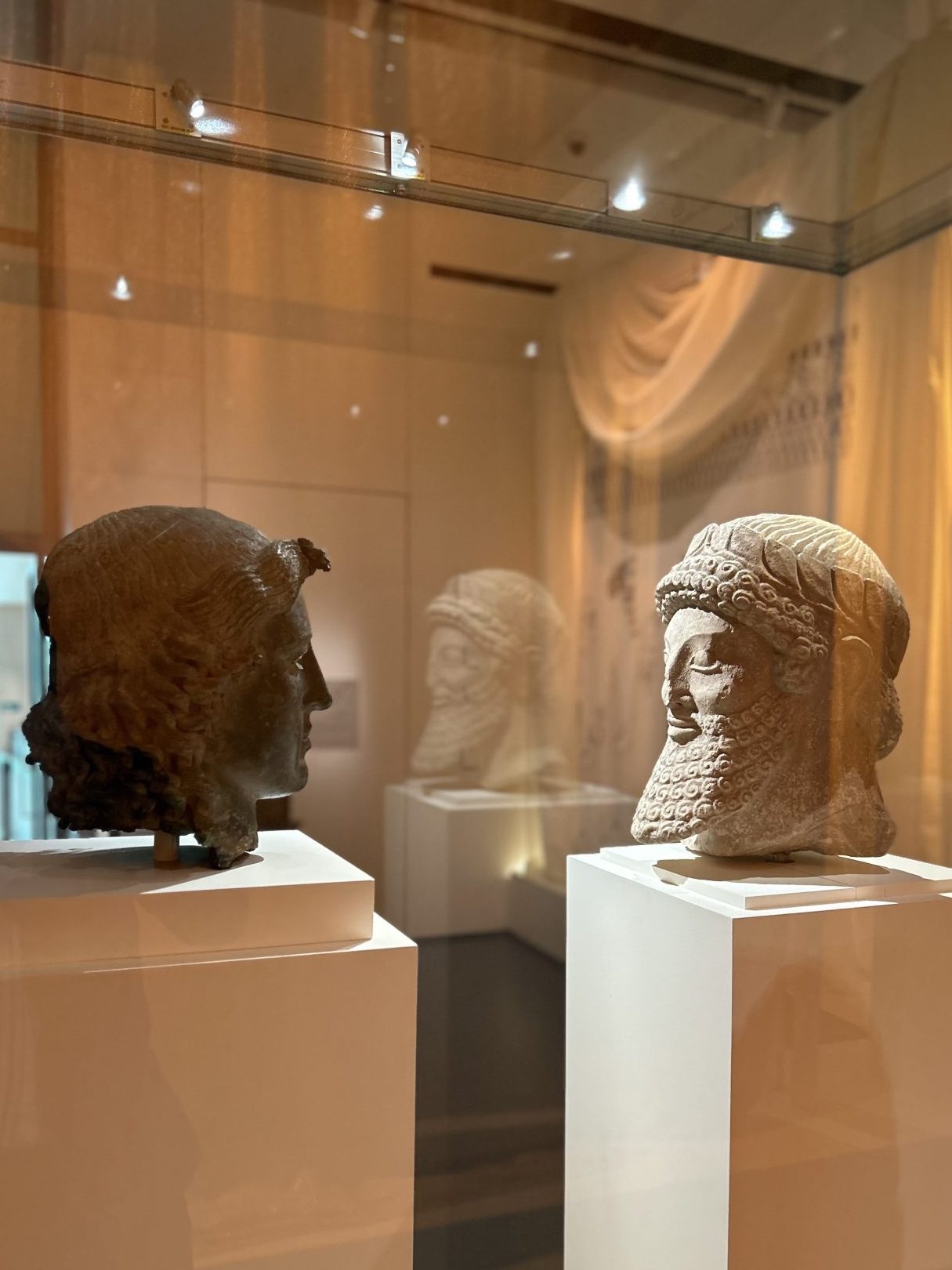 An image of two statues, one Greek and one Persian, stare at each-other in the British Museum.
