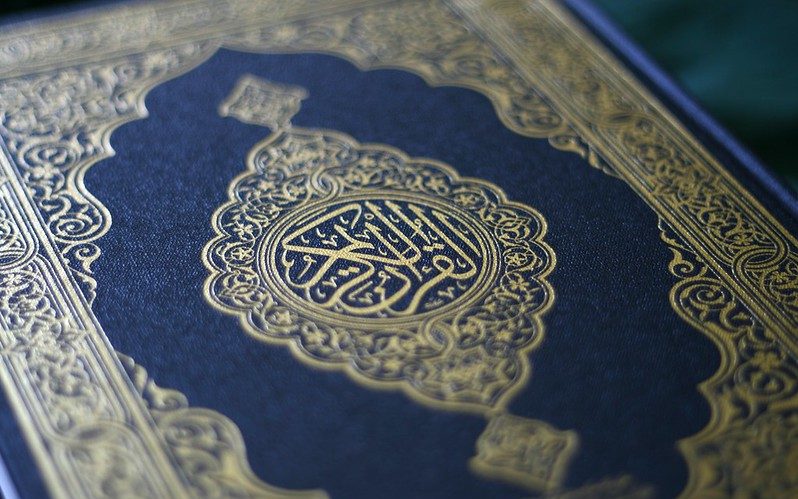 A zoomed in picture of the cover of a Koran in deep blue, with gold detailing.