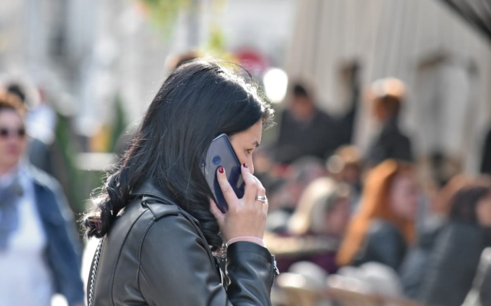 A woman is pictured holding a phone in a busy street.