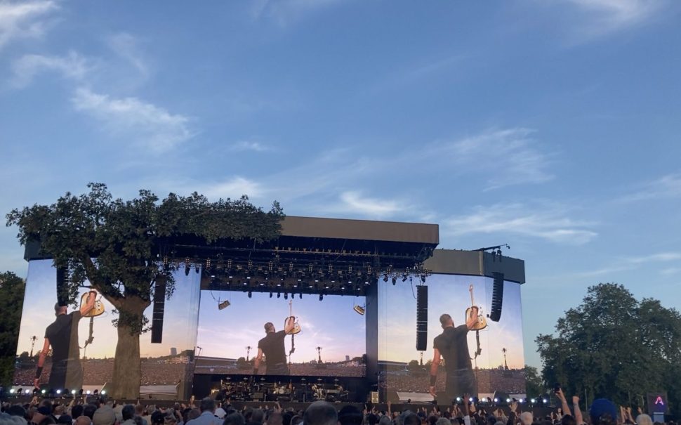 Bruce Springsteen holds his guitar high in the air after finishing a song at the Hyde Park gig