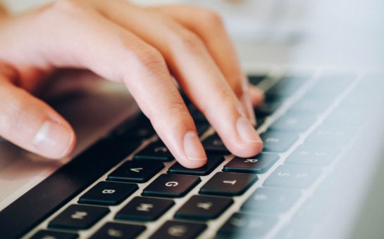 A hand typing on a keyboard
