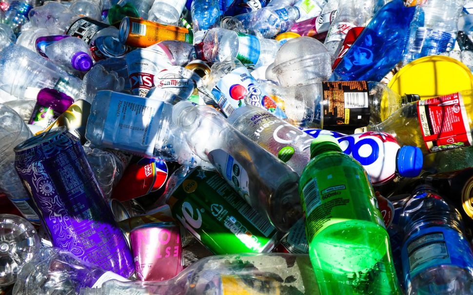 Discarded plastic bottles and cans of different colours and brands.