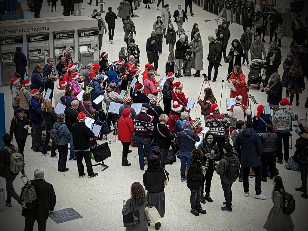 A mass busk in Waterloo Station organised by the London Ukulele Project
