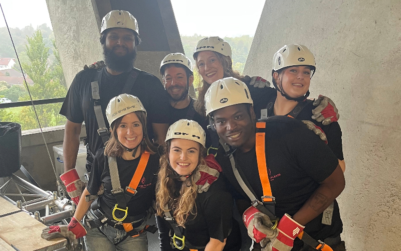 A group of fundraisers prepare to abseil from the top of the stadium. They are wearing hardhats and harnesses.