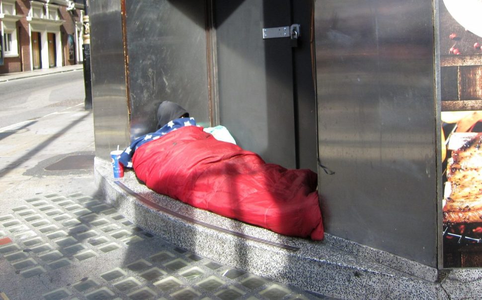 A homeless person lies in a sleeping bag in London
