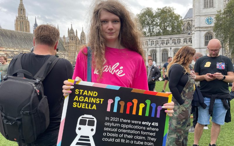 Protestor stands holding a sign outside the Houses of Parliament.