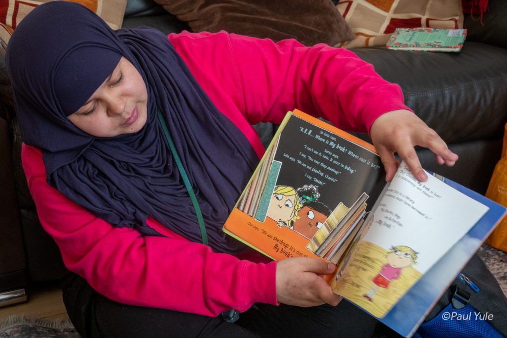 A volunteer from Doorstep Library reading a Charlie and Lola book while out on a project.