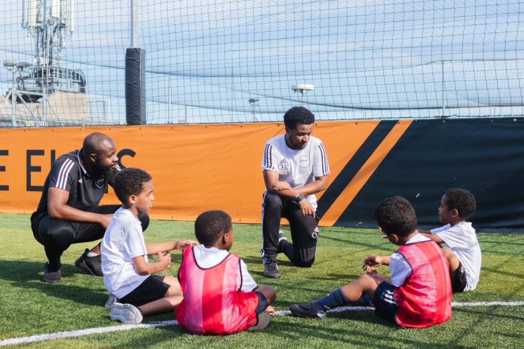 Coaches Osman Kamil and Basseriba Dembele have a team talk with Ginga players during a half term camp