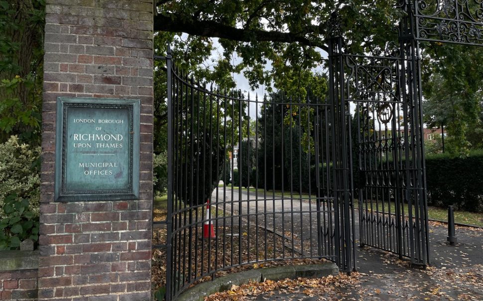 Image of the gates of Richmond council building on York street Twickenham. Large black iron gates with 'London Borough of Richmond Upon Thames Municipal Offices sigh on red brick wall.