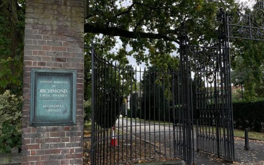 Image of the gates of Richmond council building on York street Twickenham. Large black iron gates with 'London Borough of Richmond Upon Thames Municipal Offices sigh on red brick wall.